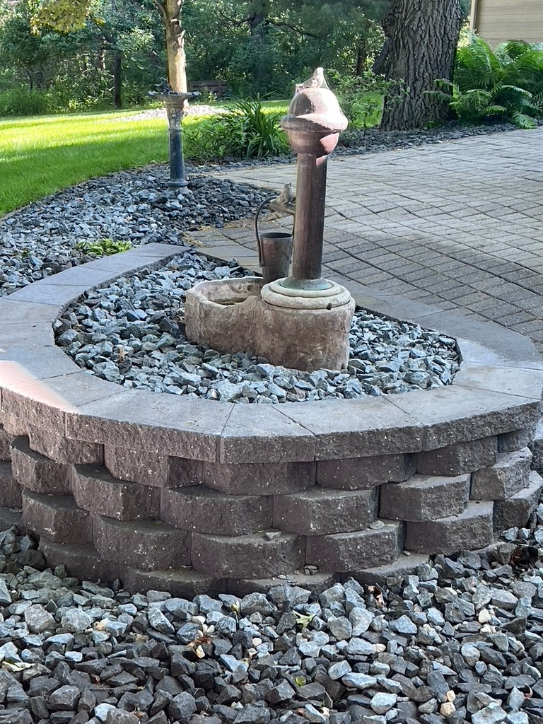Rebuilt retaining wall and landscaped backyard with vitage fountain in Elk River Minnesota