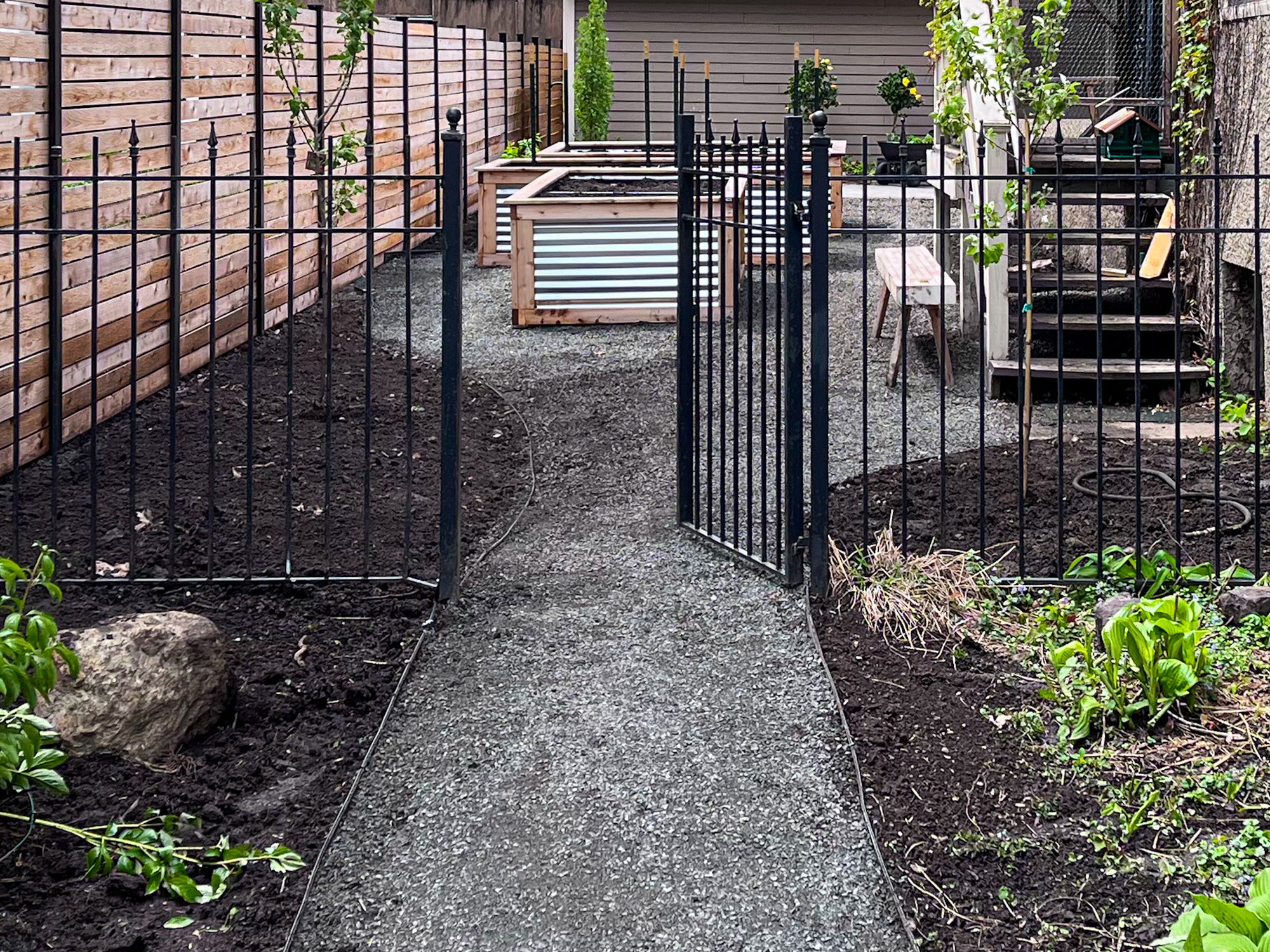 Elzo full backyard renovation with custom privacy fencing, raised garden beds, gravel paths, and planting zones in Minneapolis