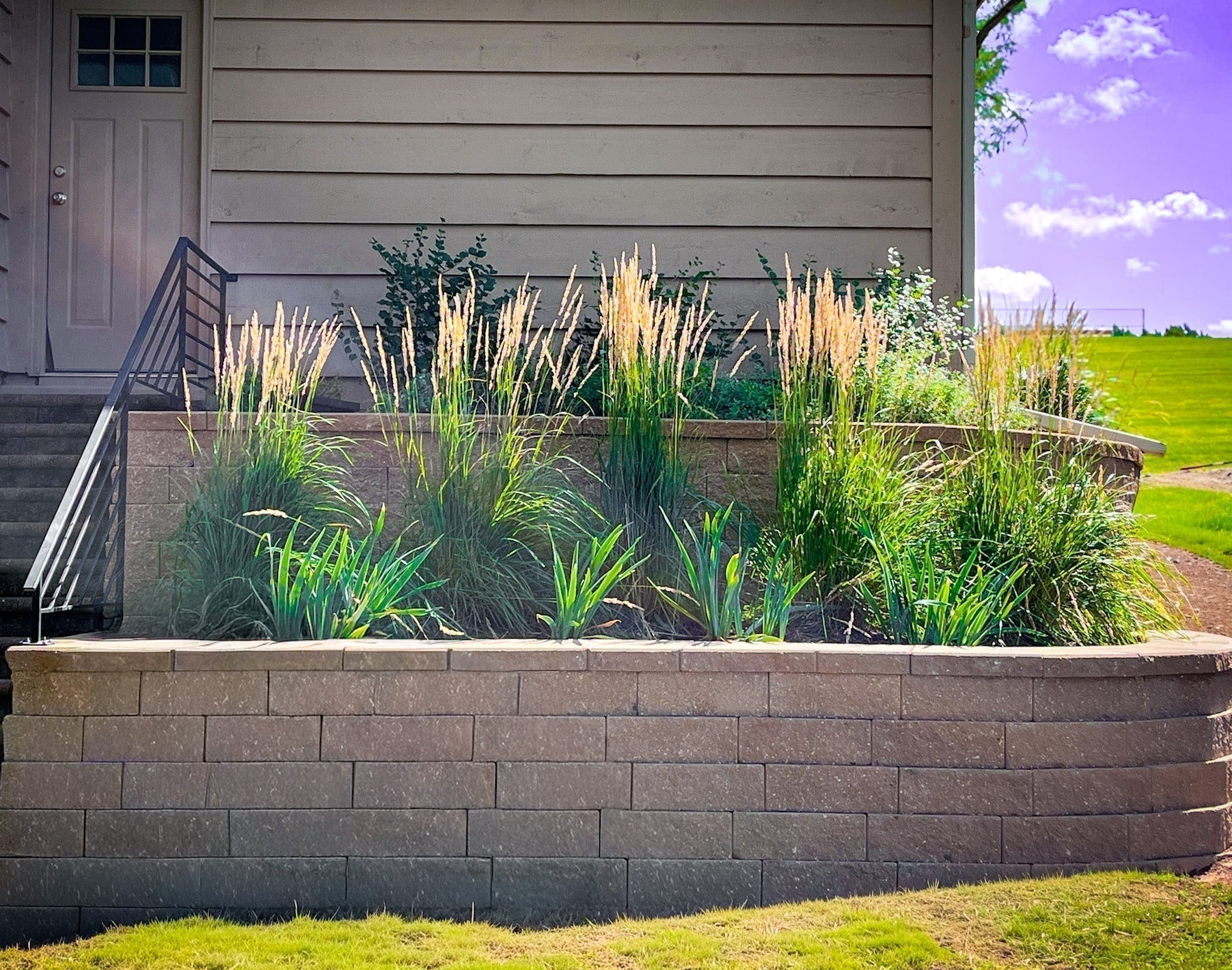 Mature ornamental grasses and perennials integrated with an Elzo retaining wall
