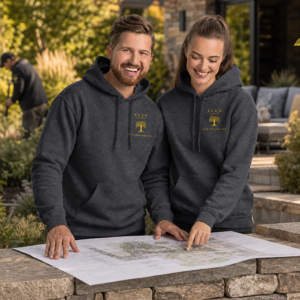 Two ELZO landscape team members wearing We Dig Beautiful hoodies while reviewing a garden plan